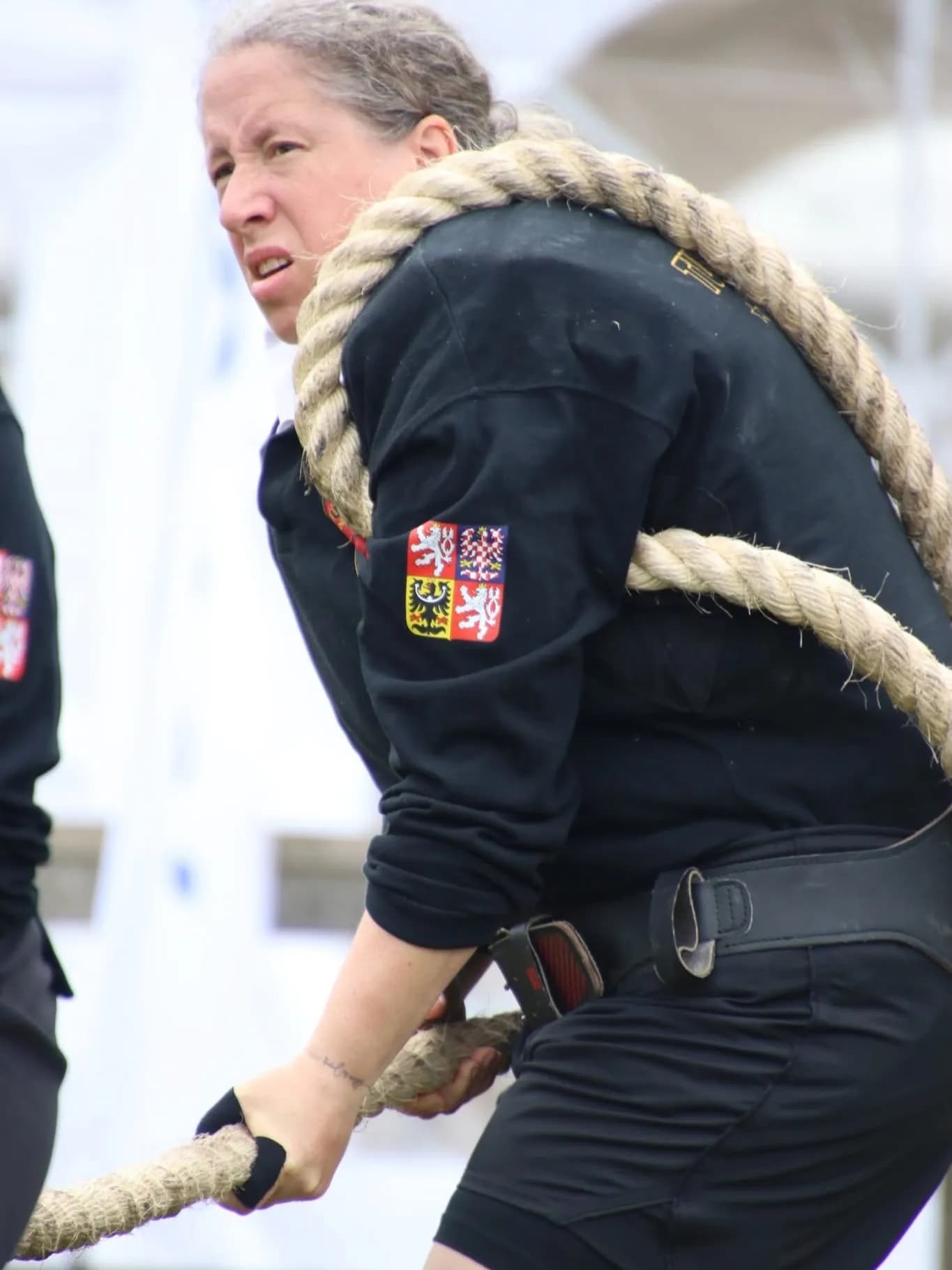 Detail: sevření lana a znak na hrudi.